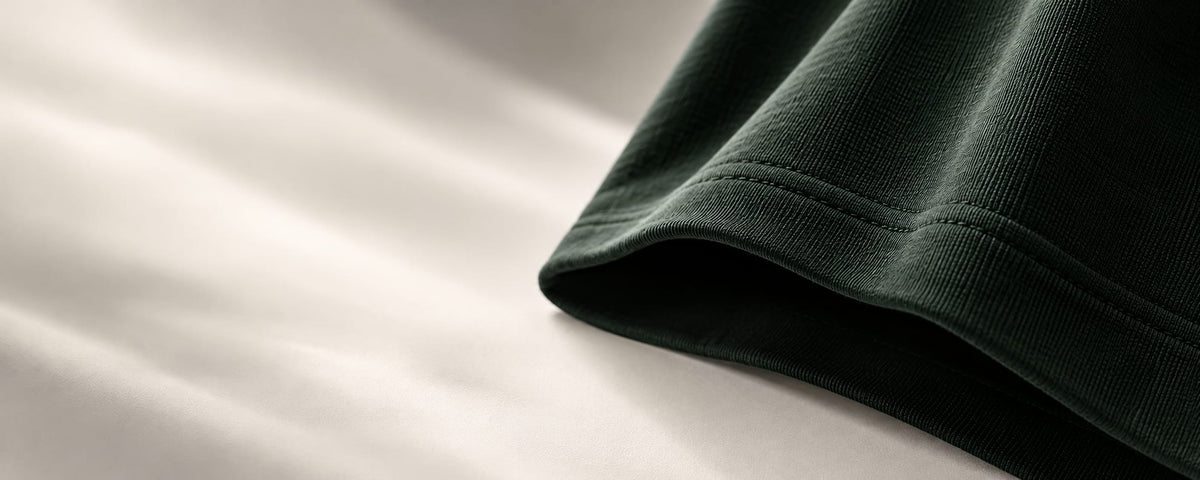 Green sleeve hem resting on cream fabric