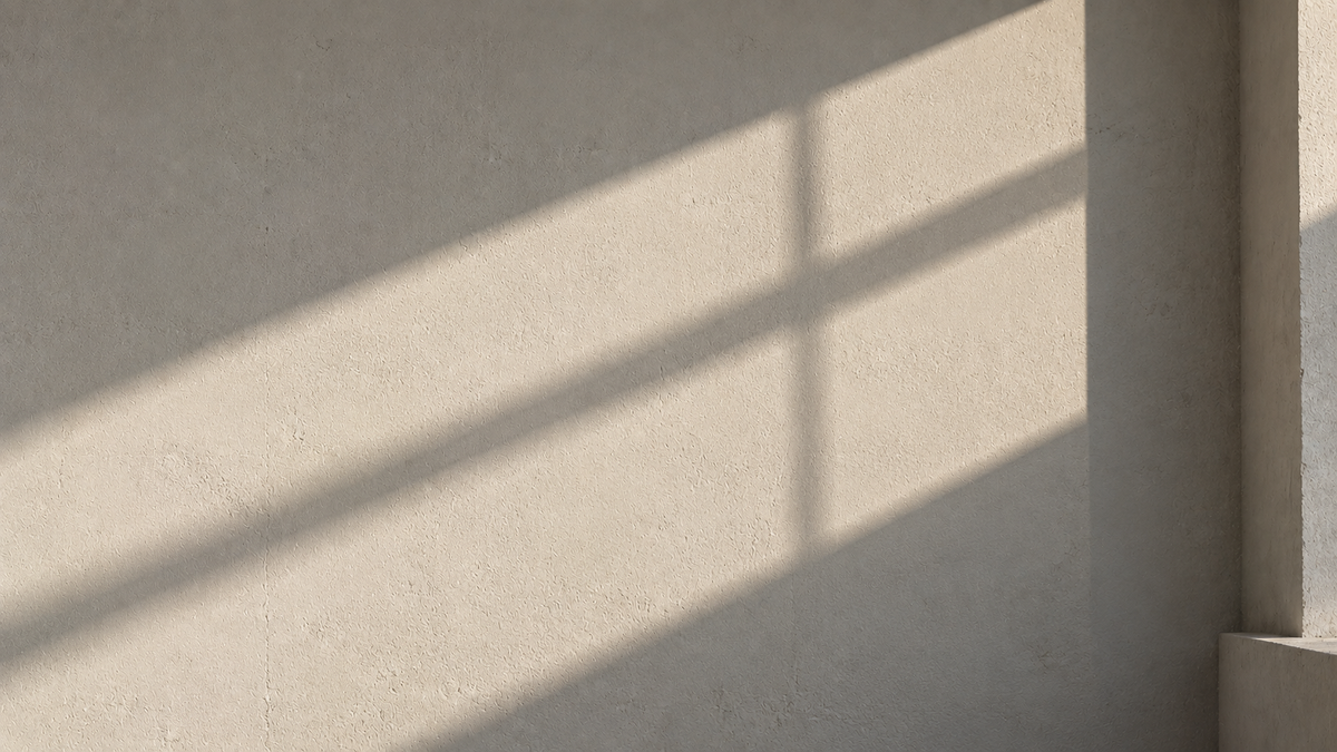 Sunlit plaster wall with a diagonal window-frame shadow